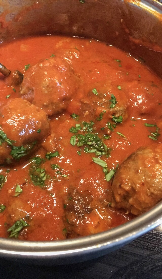 beef meatballs with tomato sauce and chopped basil in a large saucepan