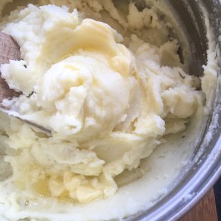 A pan of mashed potatoes with melted butter 