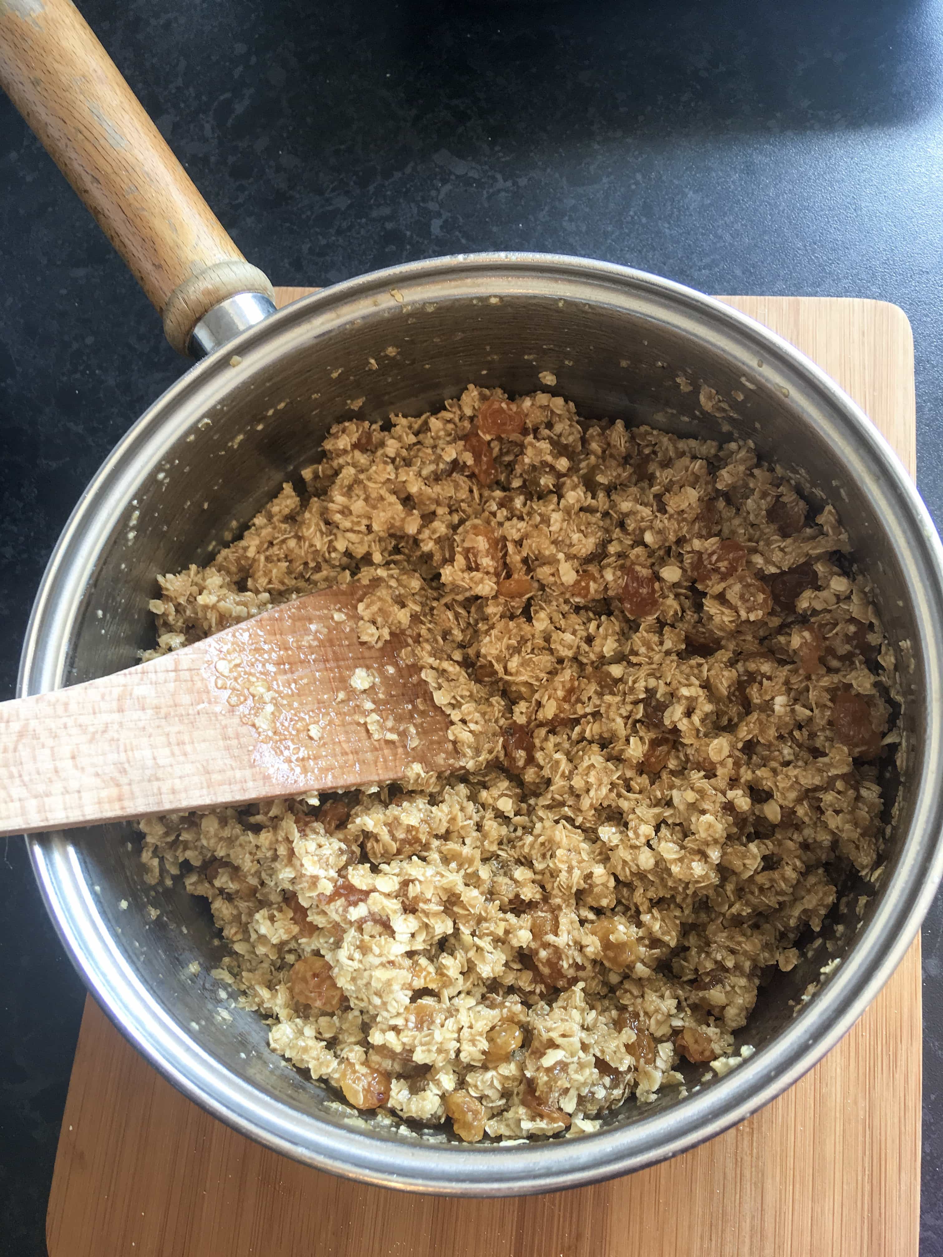 A saucepan of oats, butter, golden syrup and dried fruit for making flapjacks.