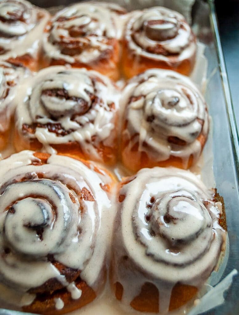 a glass dish of cinnamon rolls with pumpkin puree and covered in a maple icing glaze.