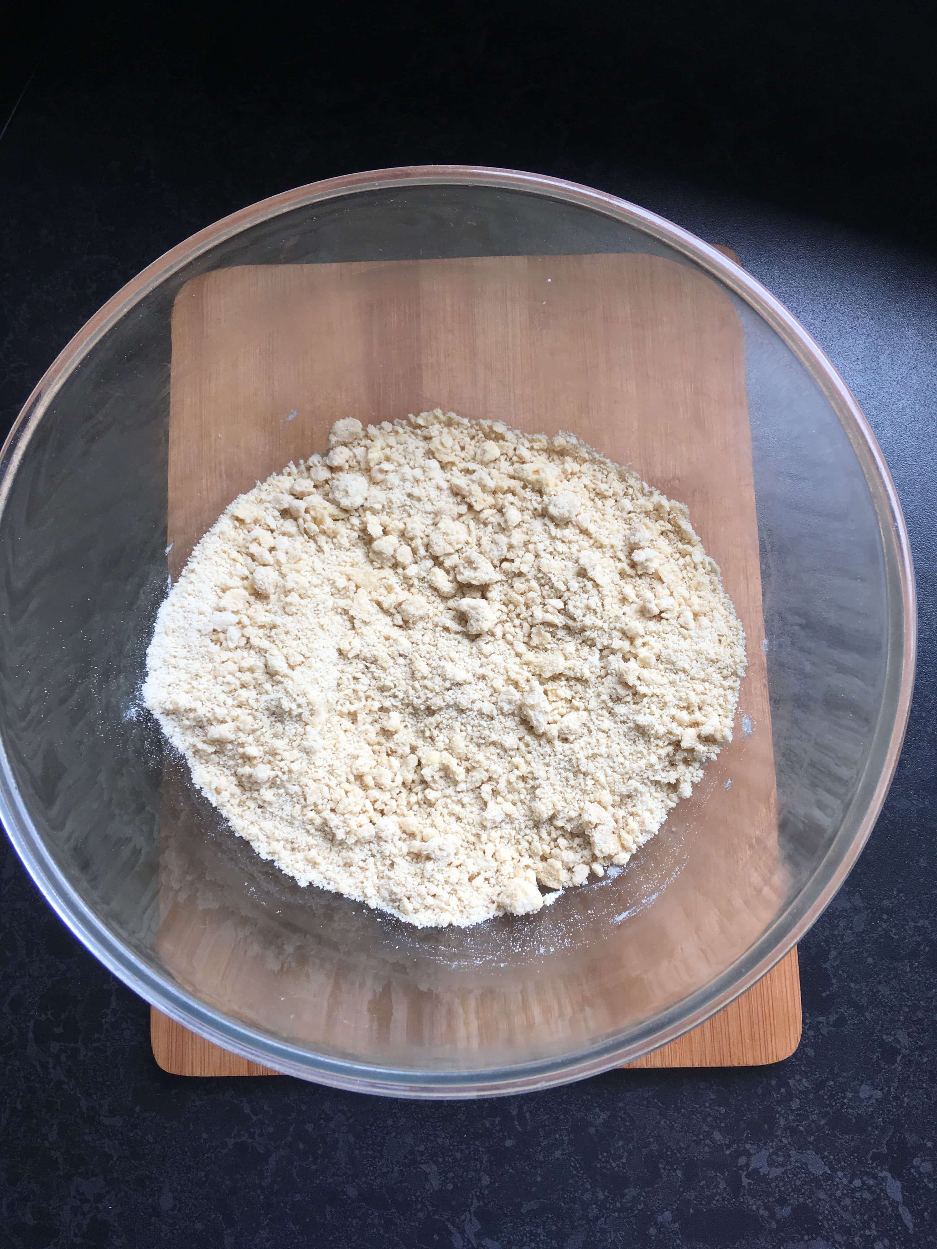 a bowl of flour and butter on a wooden chopping board.