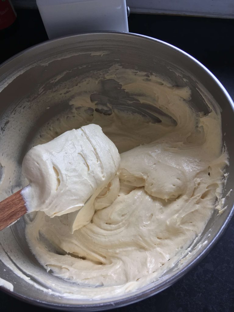 cake batter and a wooden spatula in a large silver bowl