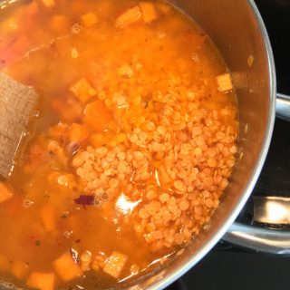 A pan of vegetables, lentils and stock for making sweet potato and lentil soup