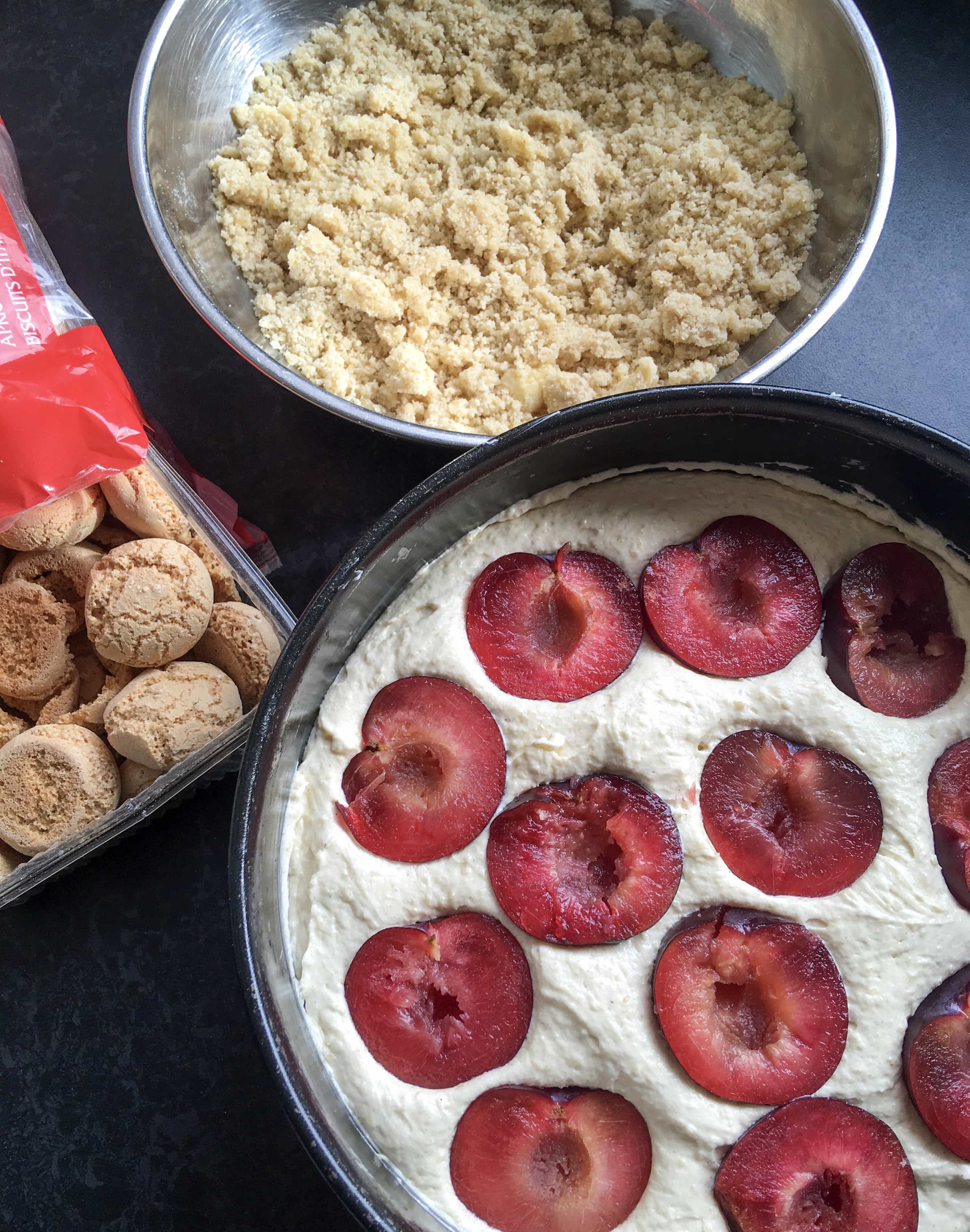 An unbaked Plum Amaretti Crumble cake - an almond sponge topped with ripe halved plums