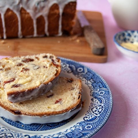 Slices of fruit loaf drizzled with an icing glaze on a willow pattern plate.