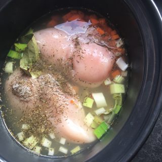 A crock pot of chicken and vegetables for making slow cooker chicken noodle soup