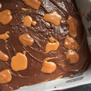 A tin of unbaked brownie batter topped with salted caramel