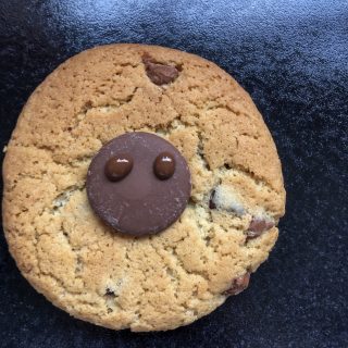 A chocolate chip cookie decorated with a chocolate button