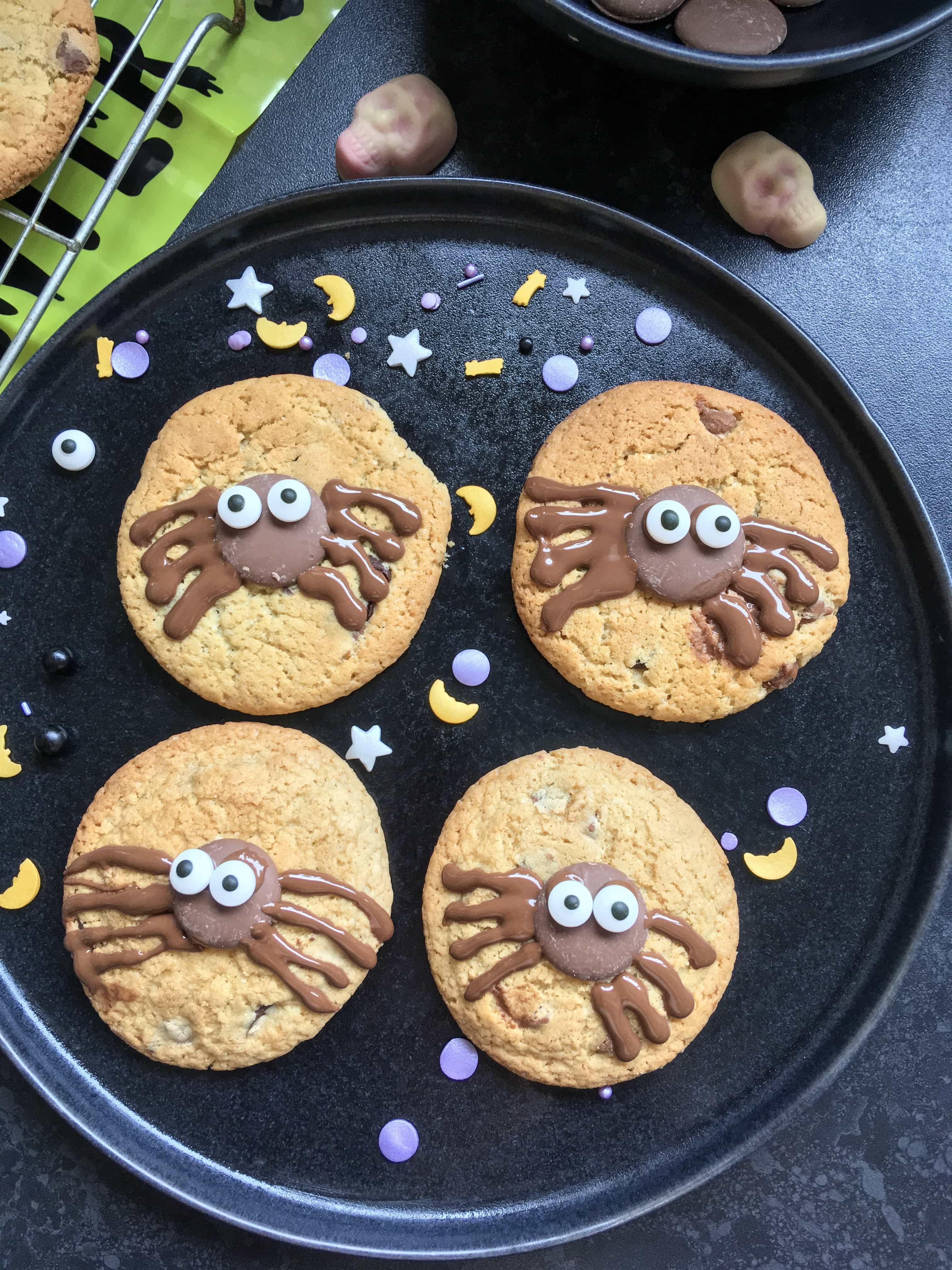 A plate of chocolate chip cookies with a chocolate spider decoration. 