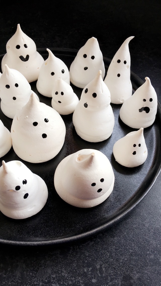 white meringue ghosts on a black plate