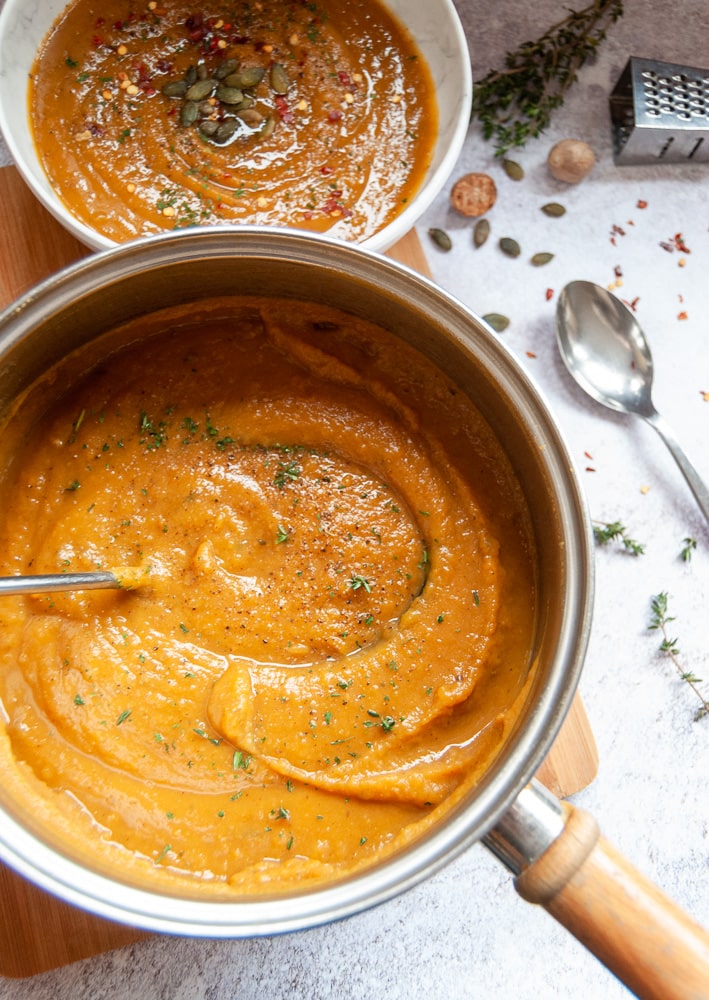 A pan of butternut squash soup sprinkled with herbs.