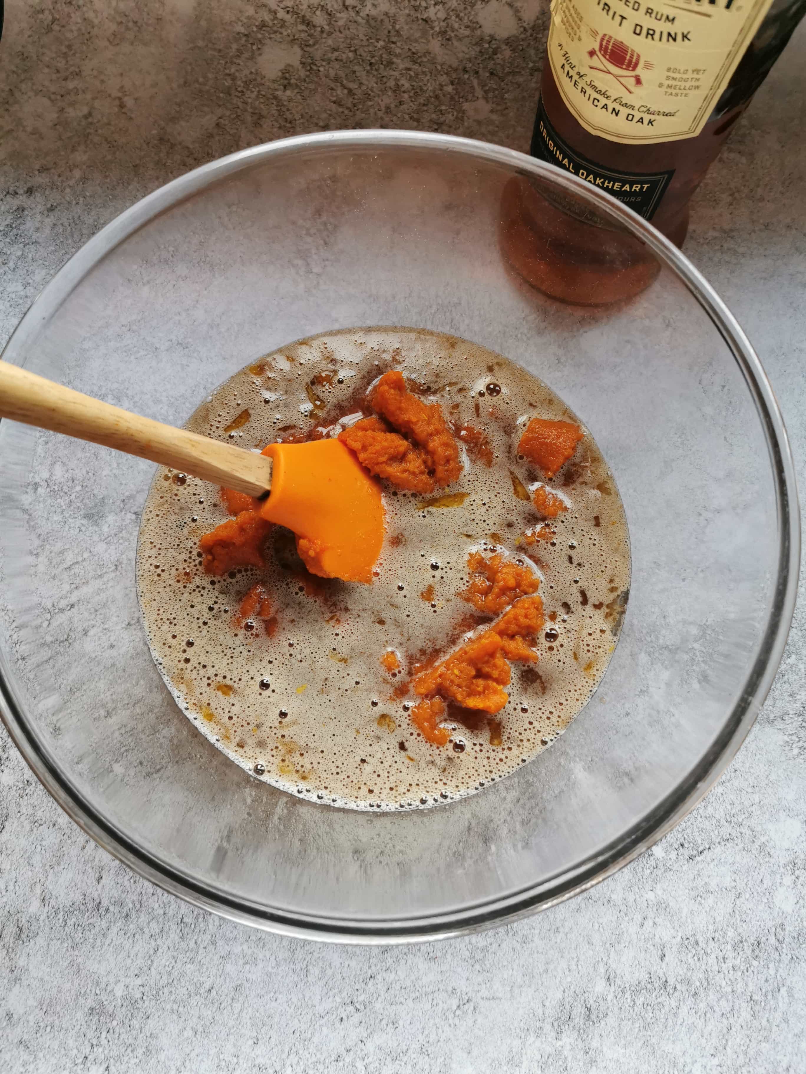 A bowl of melted butter, brown sugar, pumpkin puree, rum and spices for making pumpkin pie filling.