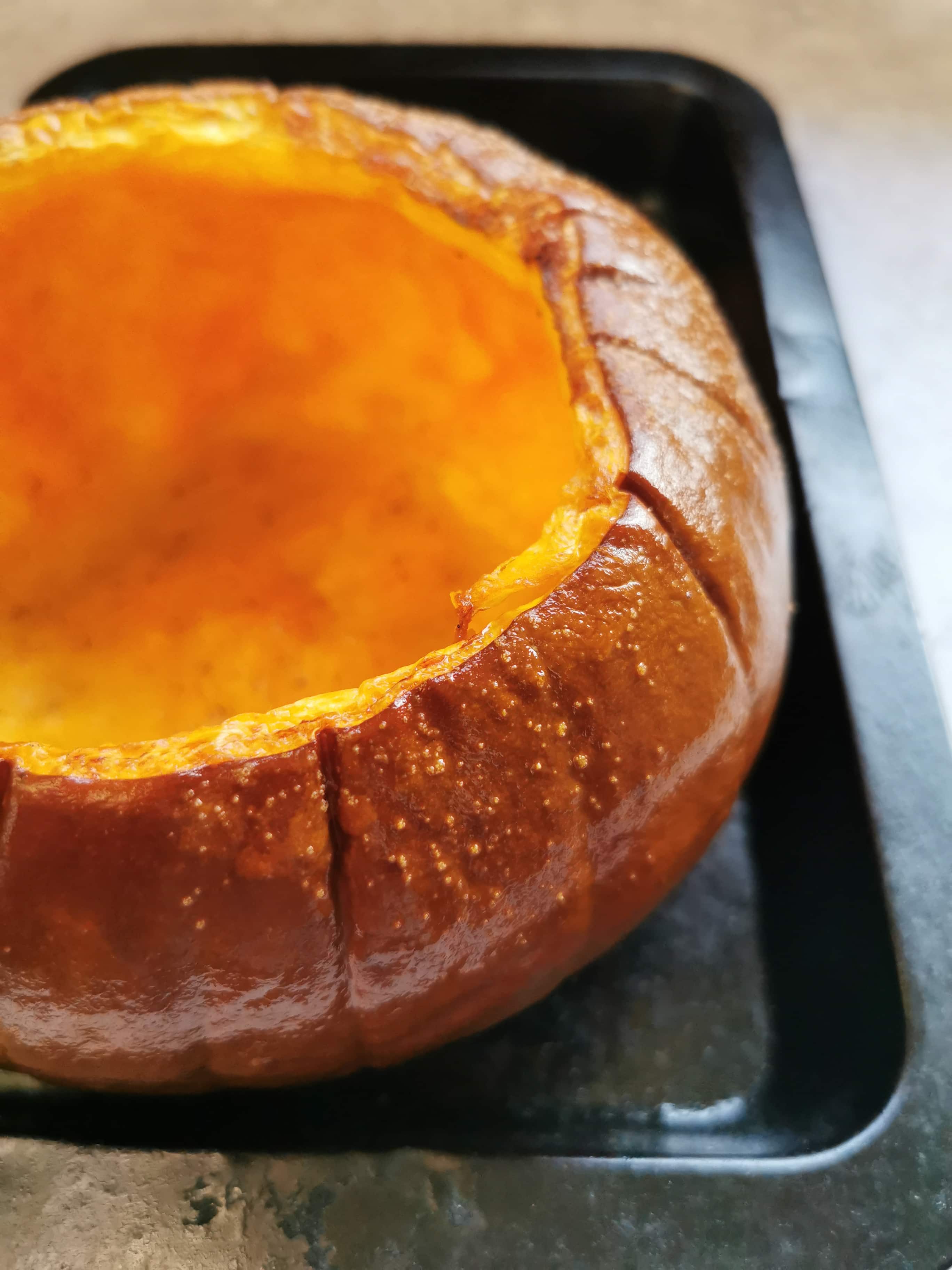 A pumpkin with the seeds scraped out in a baking tin ready for roasting.
