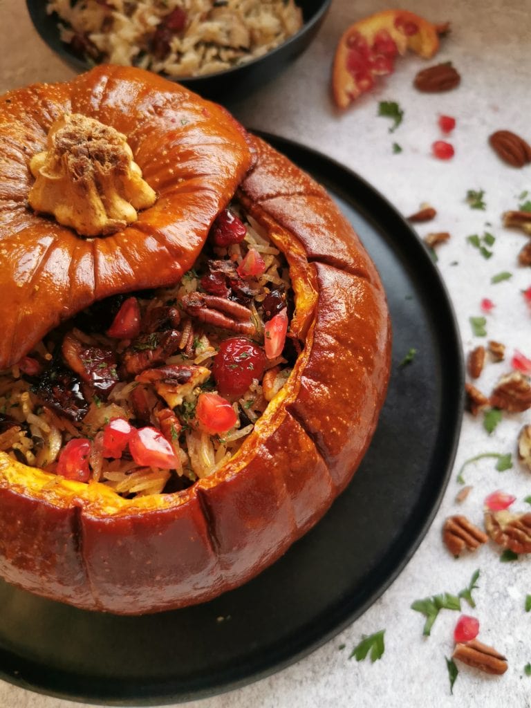 A roasted stuffed pumpkin filled with rice, mushrooms, cranberries, herbs and topped with pomegranate seeds.