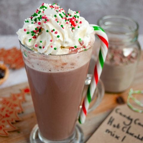 A glass of Candy cane hot chocolate with whipped cream, crushed candy canes and Christmas sprinkles