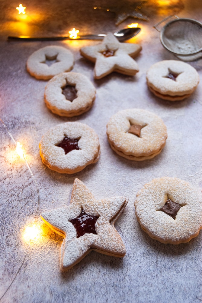 Christmas Linzer star cookies filled with jam and dusted with icing sugar surrounded by fairy lights.