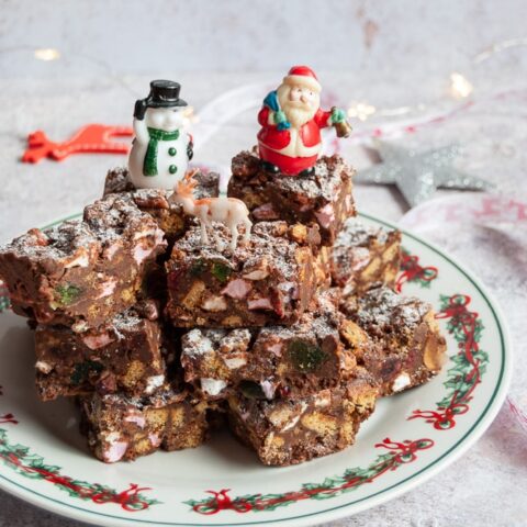 rocky road bars piled up on a Christmas plate with santa, snowman and reindeer figures.