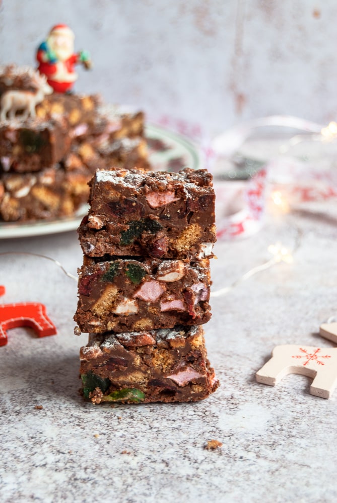 three pieces of rocky road piled on top of each other, red and white reindeer christmas decoations and red and white ribbon.