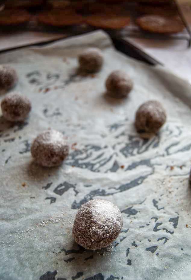Cookie balls sprinkled with sugar on a baking tray