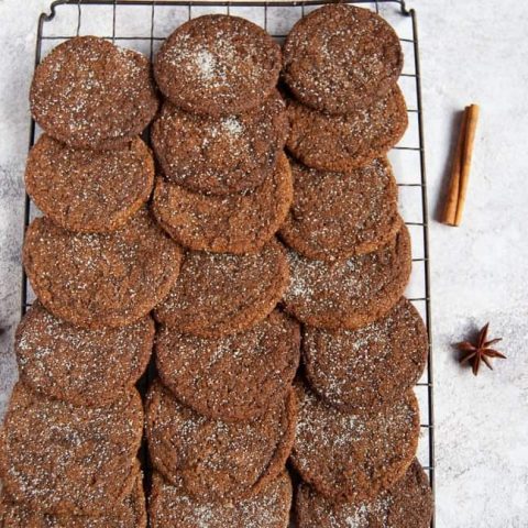 Ginger cookies on a wire rack with silver Christmas decorations for a festive scene