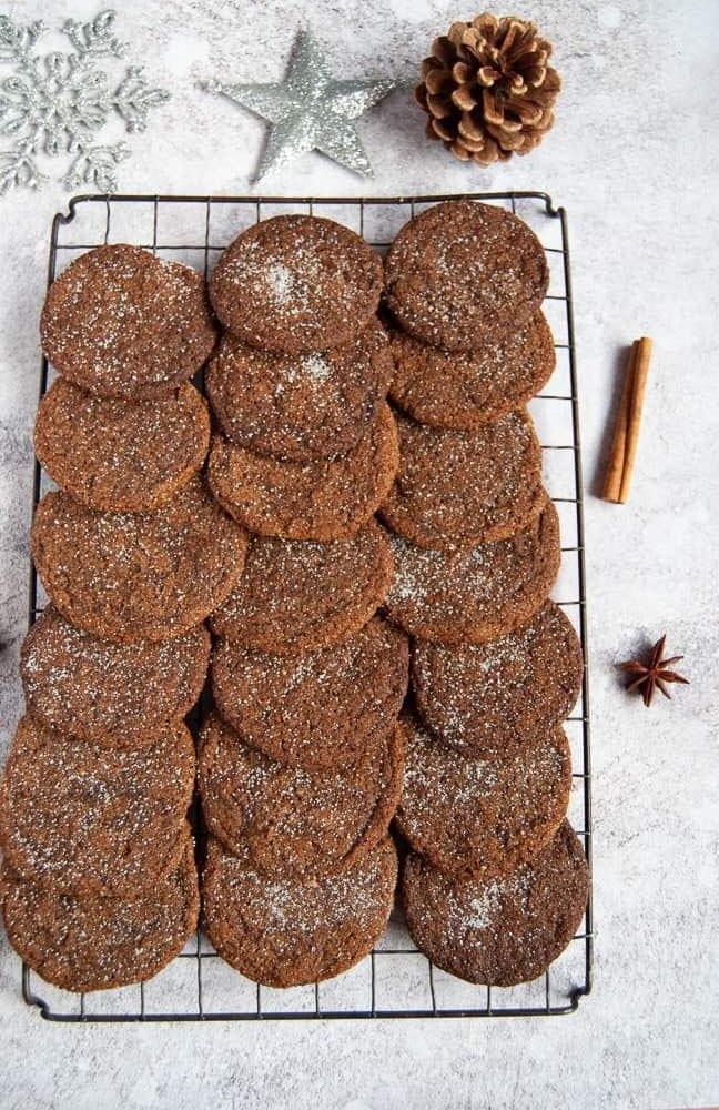 Ginger cookies on a wire rack with silver Christmas decorations for a festive scene