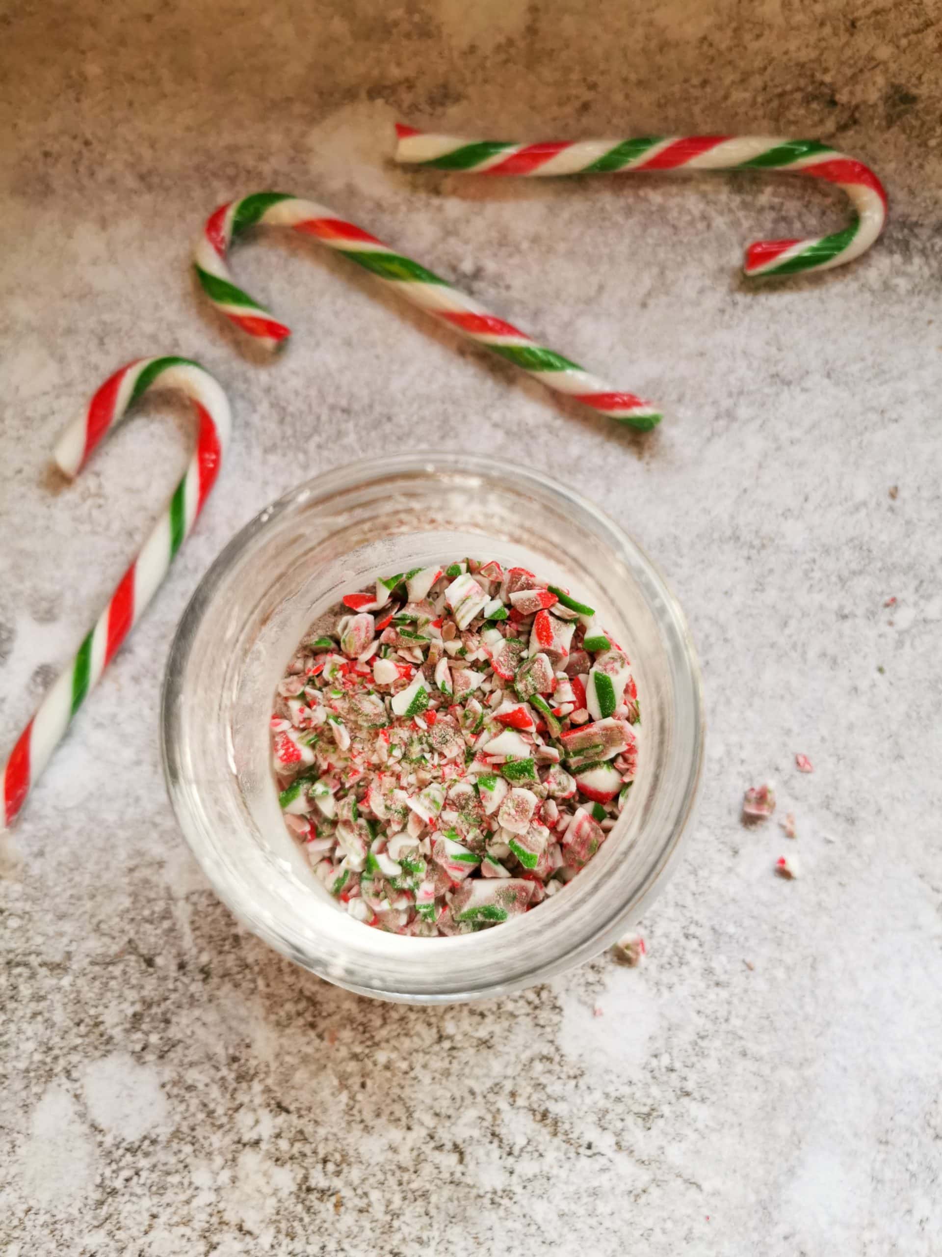 Crushed candy canes in a glass jar on a grey and white background 