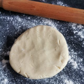 A ball of cookie dough on a floured work surface ready to be rolled out