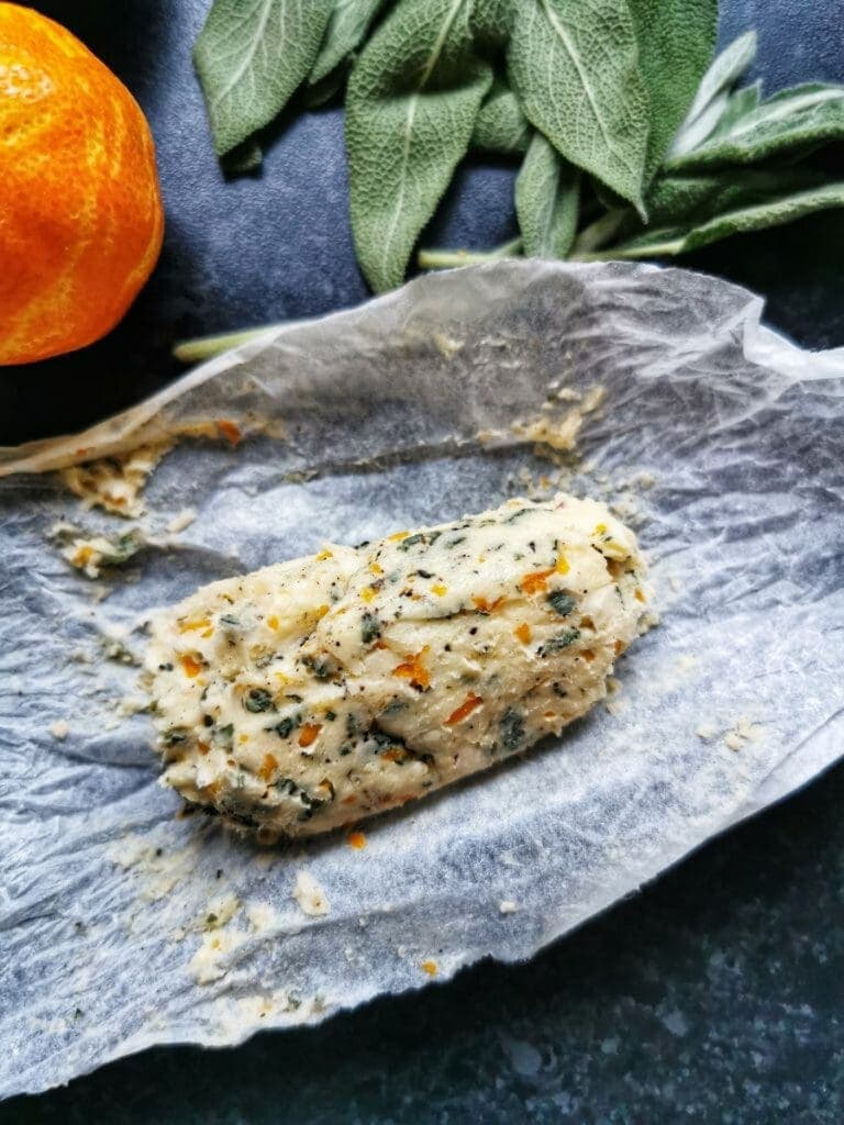 A log of sage and orange flavoured butter on a piece of greaseproof paper 