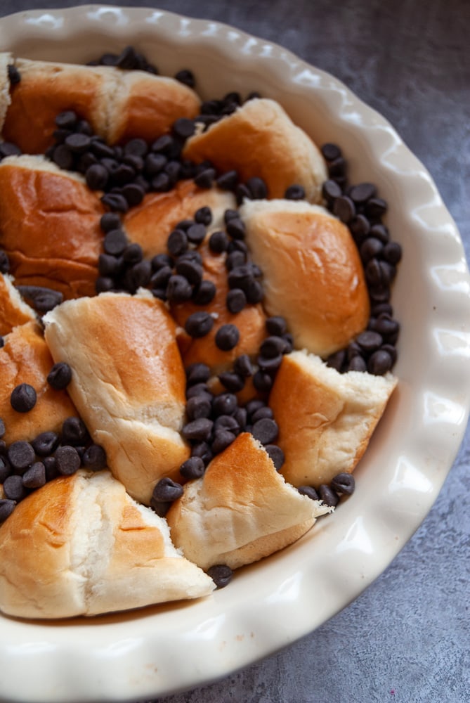 A round white dish full of brioche pieces and chocolate chips