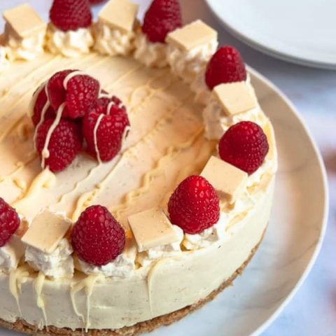 A no bake white chocolate and raspberry cheesecake on a white plate