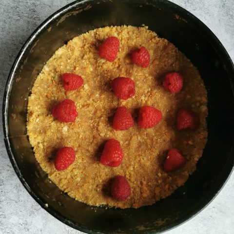 A springform Round cake tin with a biscuit base and fresh raspberries 
