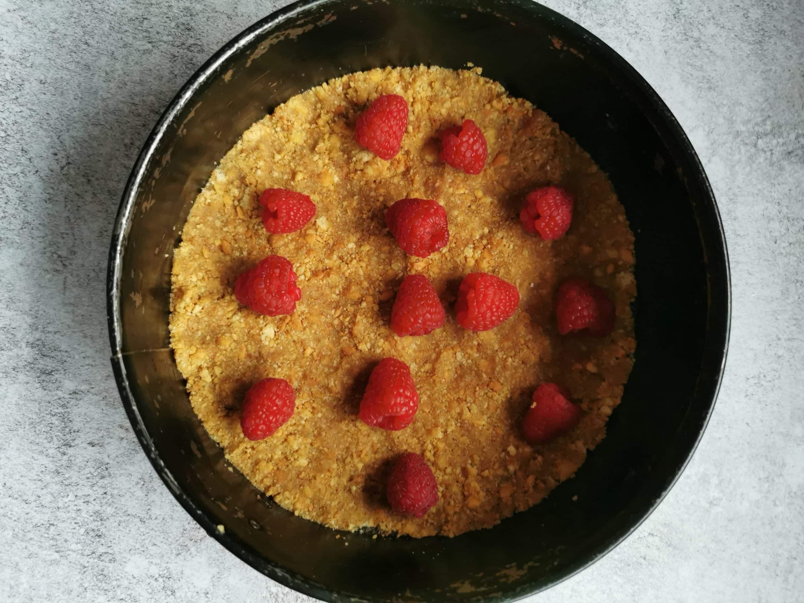 A springform Round cake tin with a biscuit base and fresh raspberries 