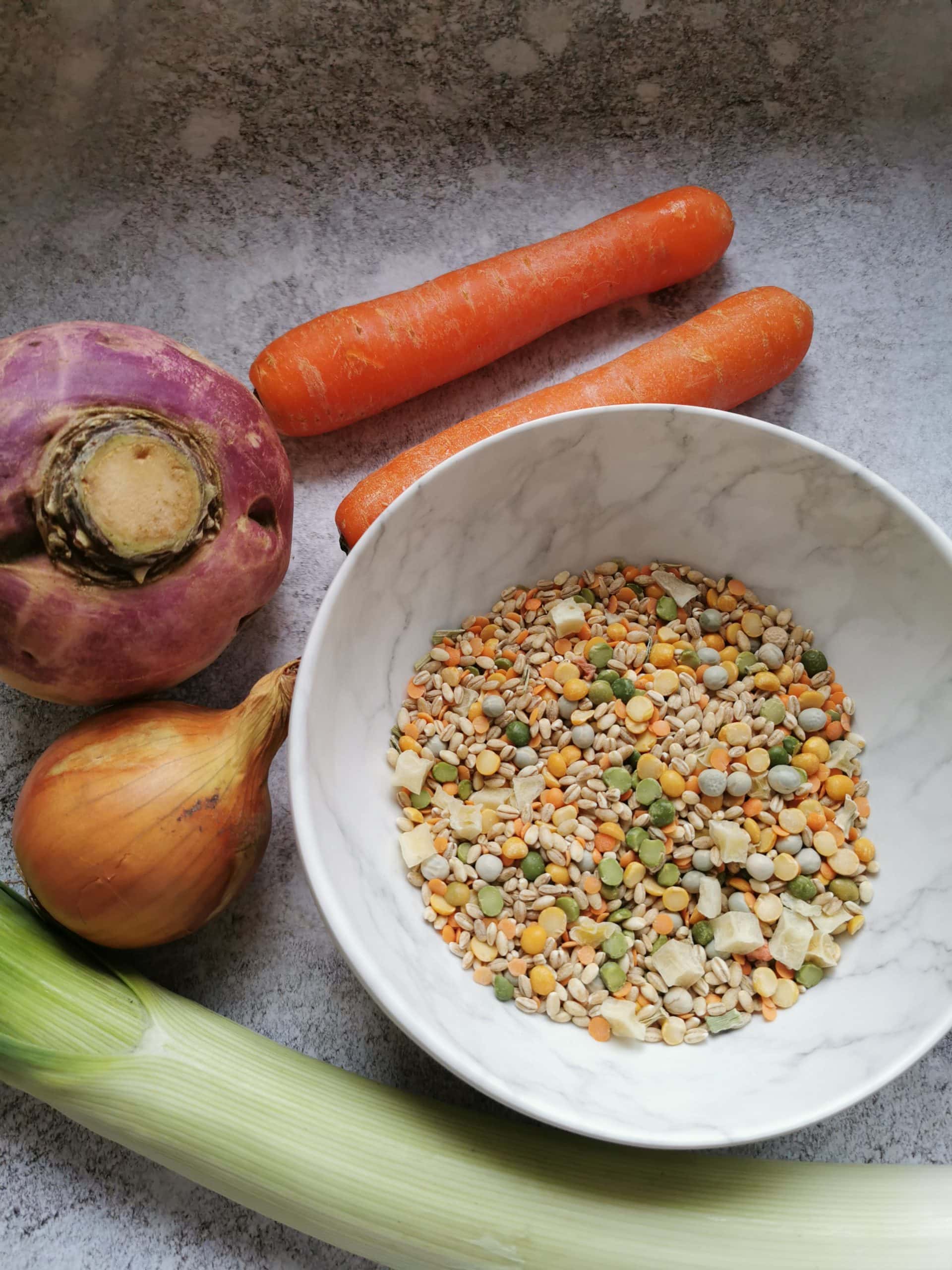 A bowl of broth mix and carrots, leeks, onion and turnip