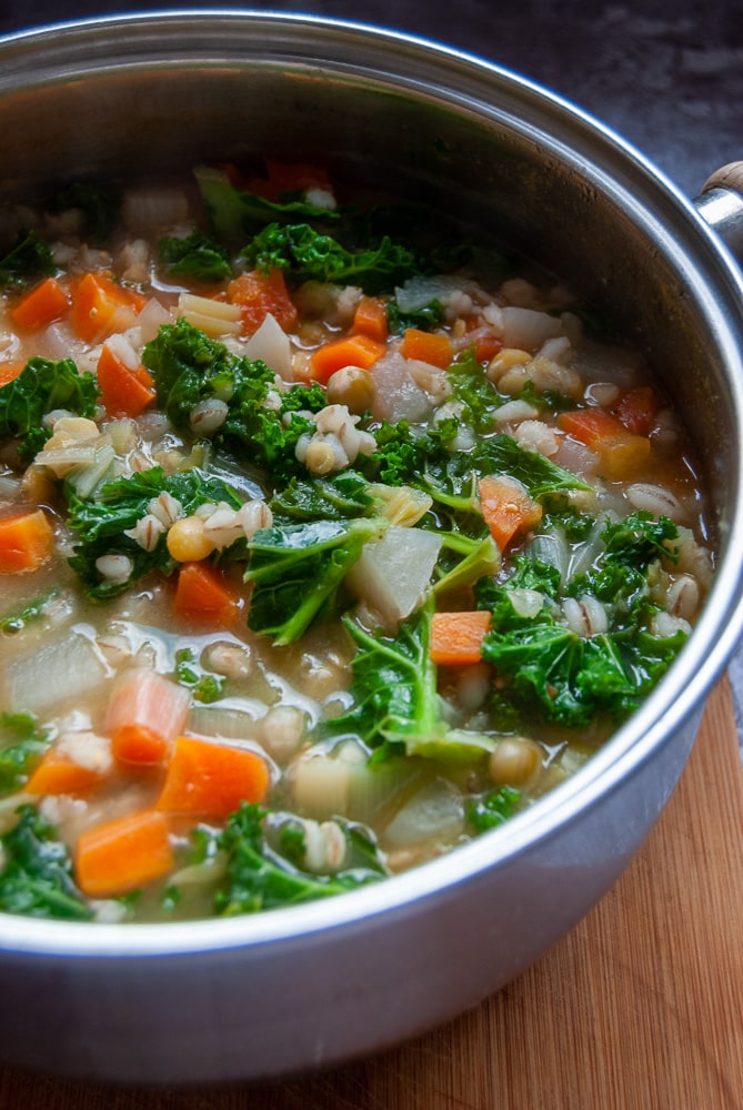 A pan of vegetarian scotch broth with carrots, leek, broth mix and kale.