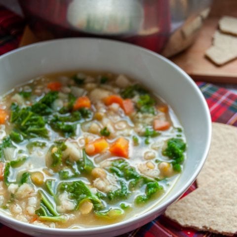 A bowl of Scotch Broth with carrots, leeks and Kale with oatcakes on the side