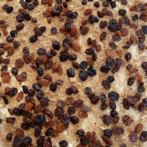 Chelsea bun dough sprinkled with spiced sugar and dried fruit