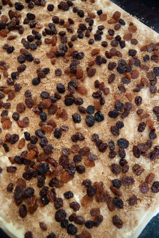 Chelsea bun dough sprinkled with spiced sugar and dried fruit