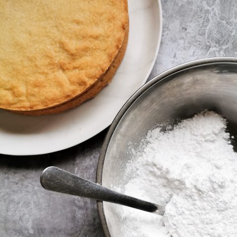 A round piece of shortbead and a bowl of icing sugar