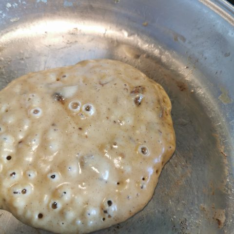 A brown sugar pancake cooking in a frying pan