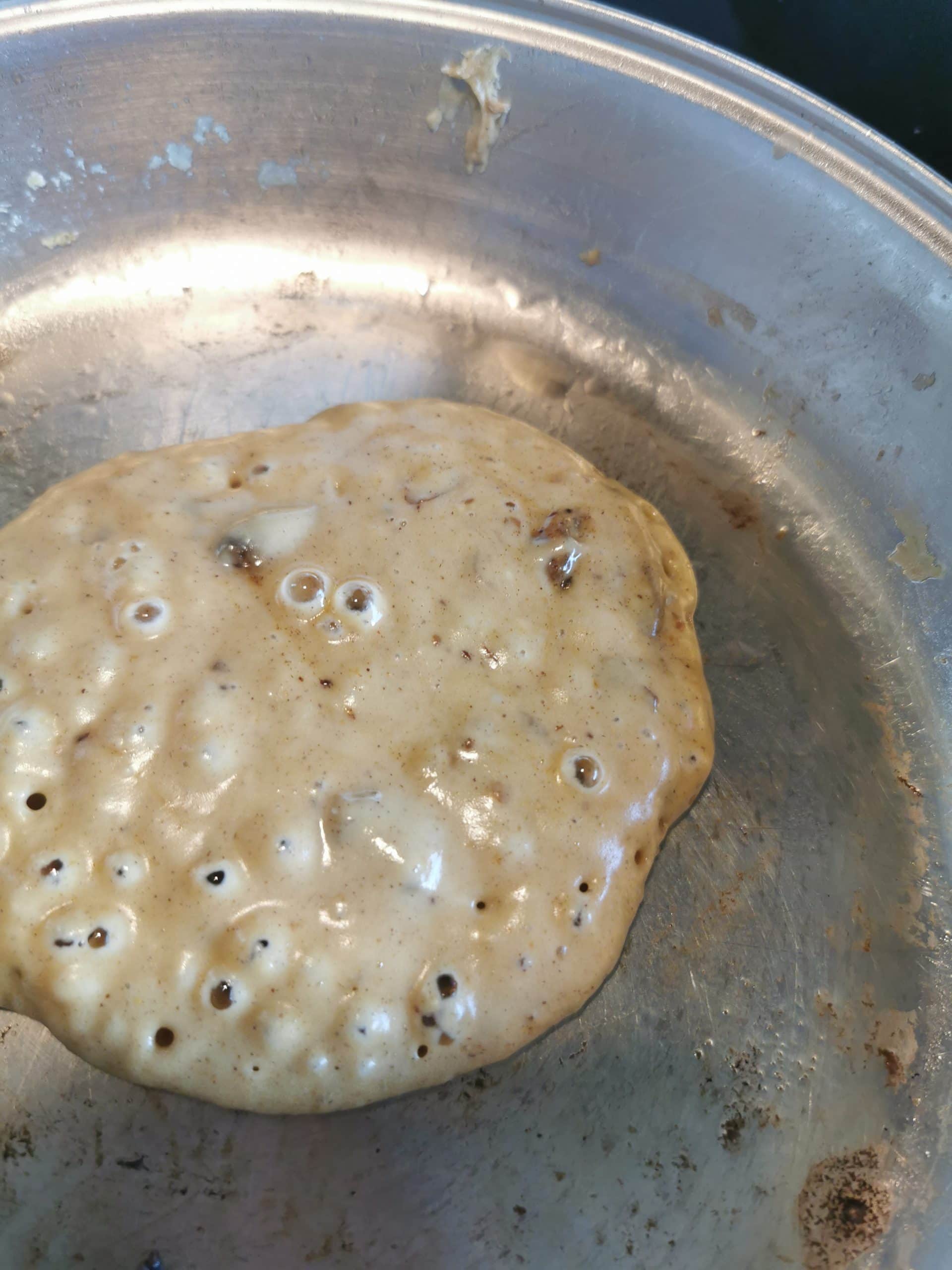 A brown sugar pancake cooking in a frying pan