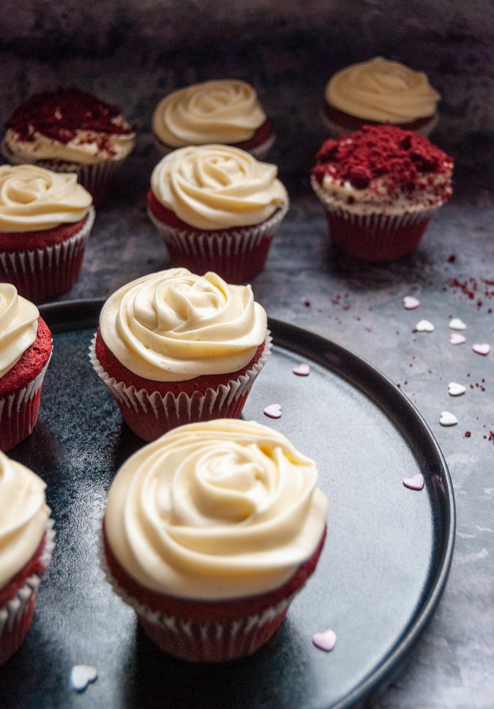 Red velvet cupcakes with cream cheese frosting on a black plate/grey background 