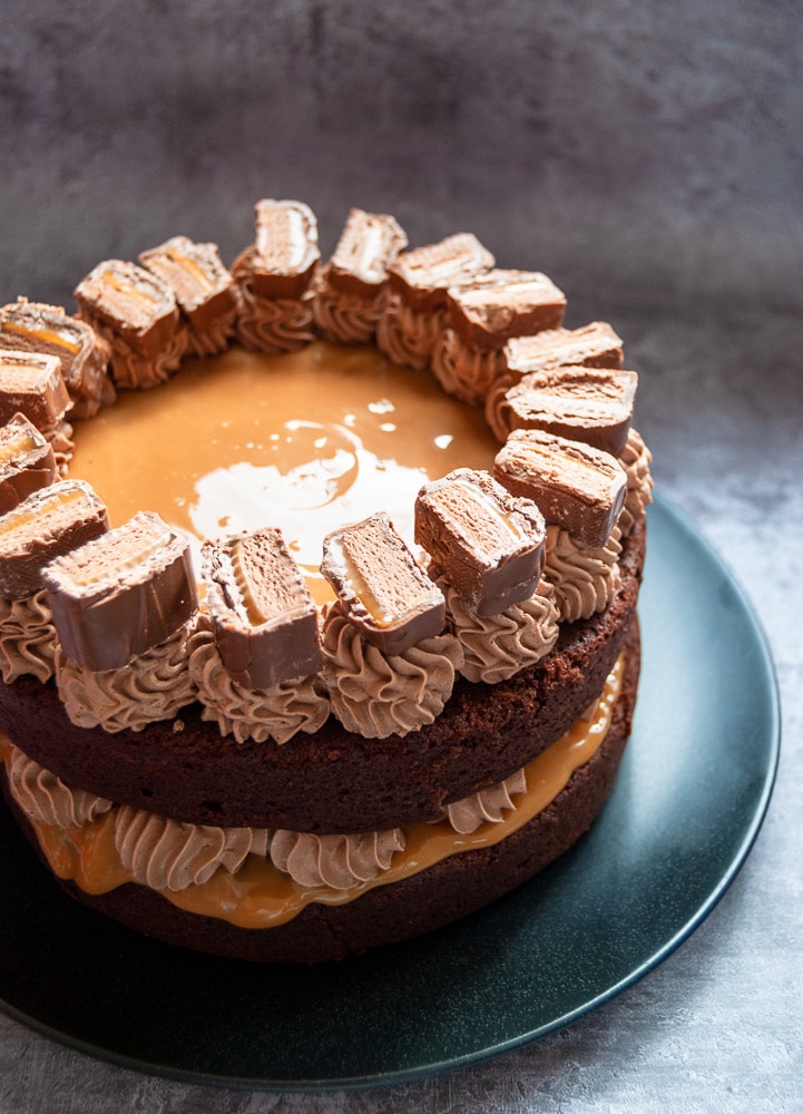 A chocolate cake filled with caramel and decorated with chocolate buttercream and chopped mars bars