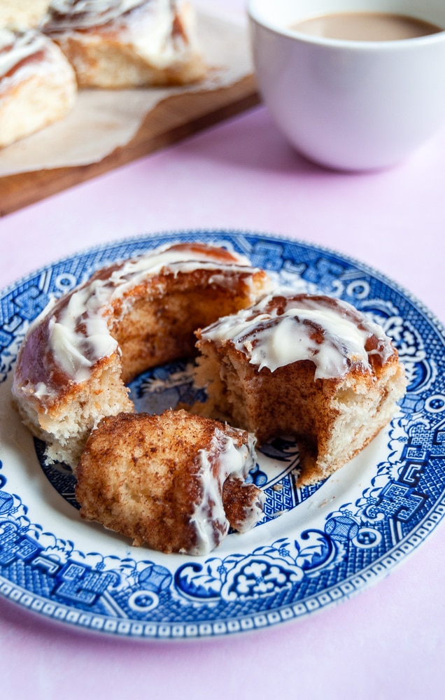 Pieces of cinnamon roll on a blue plate and a cup of coffee.