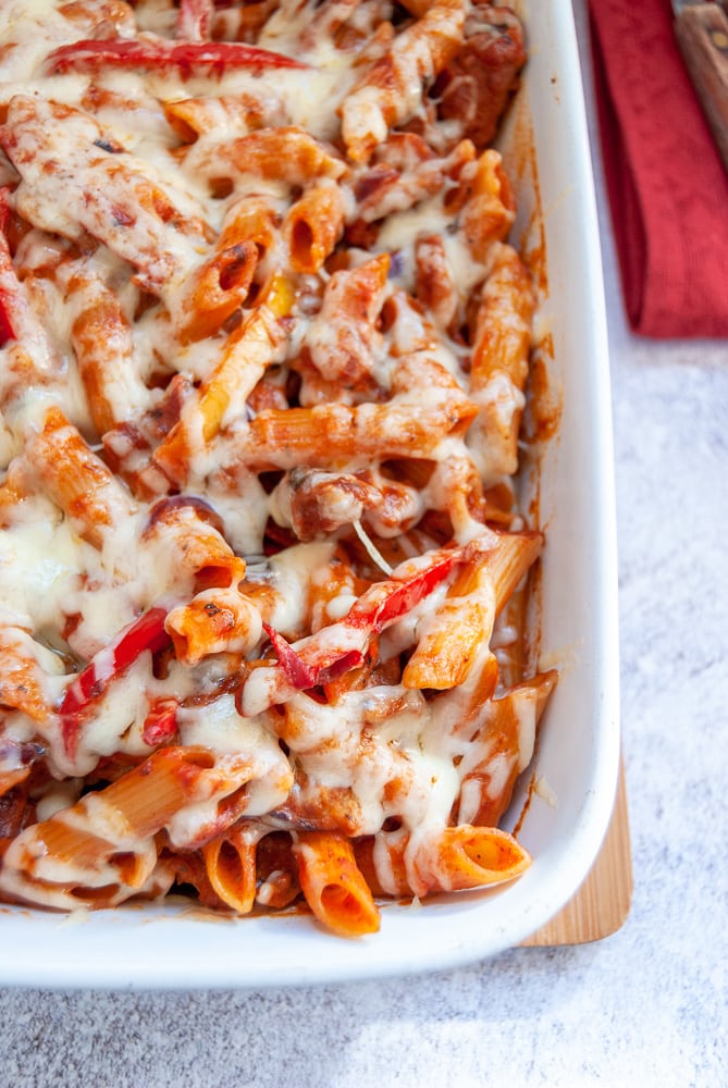 A dish of penne pasta with chicken, onions and peppers in a spicy tomato sauce.