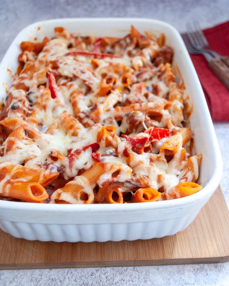 A dish of pasta with onions and peppers in a spicy tomato sauce and covered in grated cheese