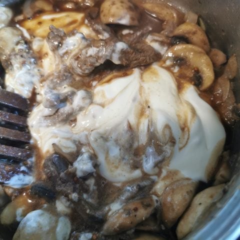 A pan of onions, mushrooms, beef stock and sour cream