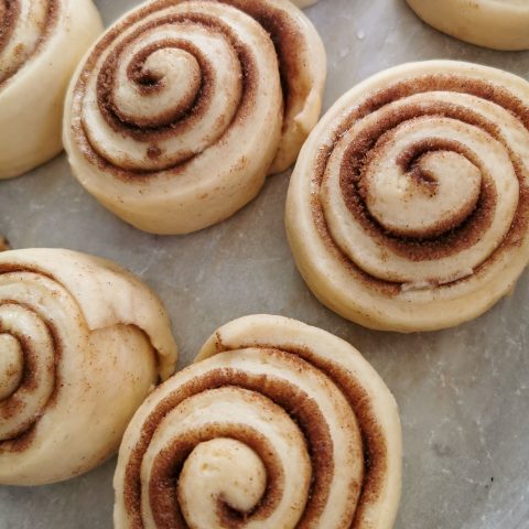 a batch of unbaked cinnamon rolls on a baking tray