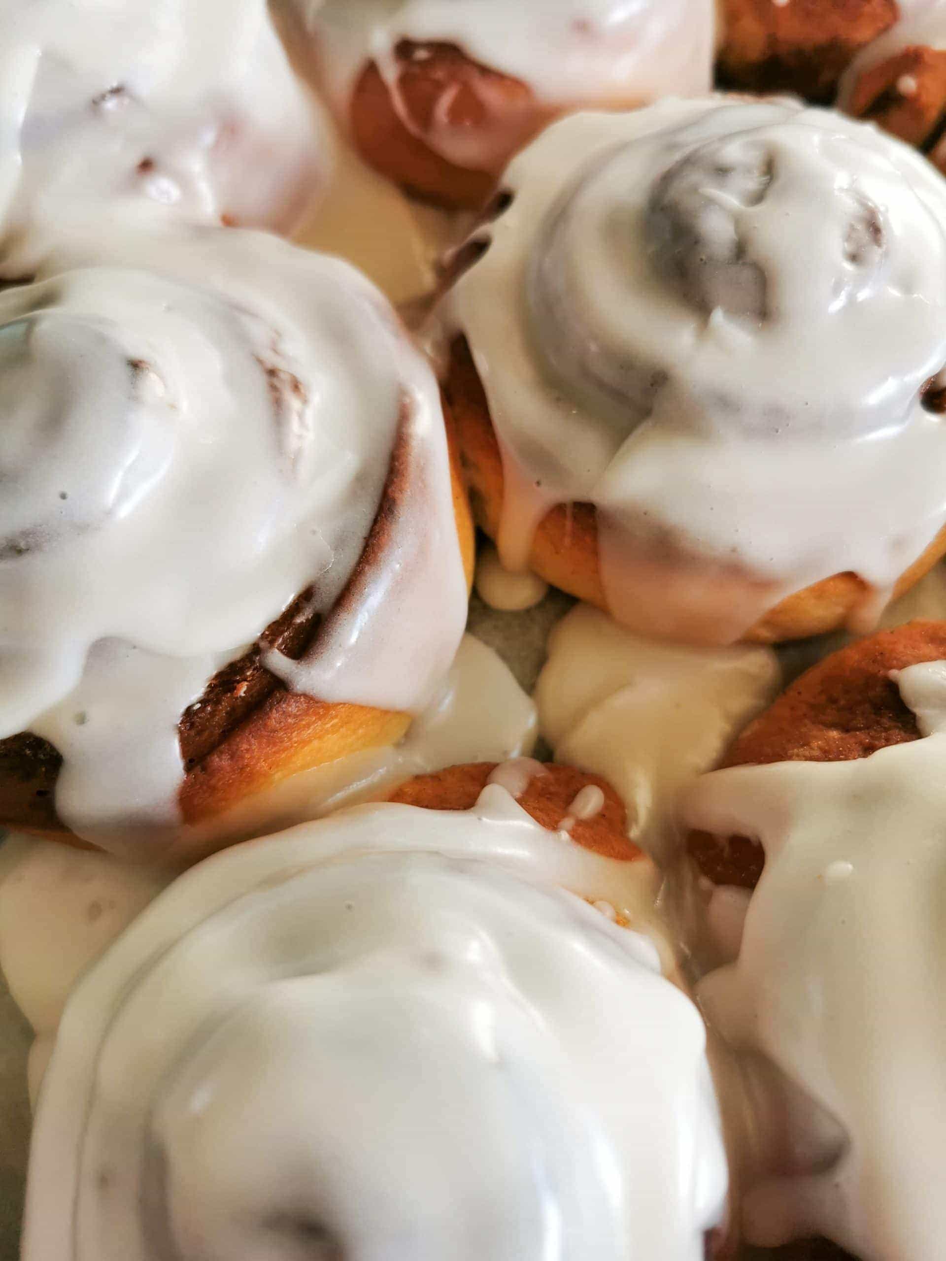 A batch of cinnamon rolls covered in vanilla icing glaze