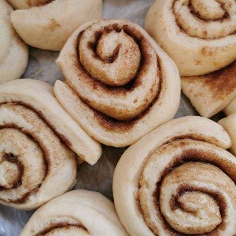 A batch of unbaked cinnamon rolls in a baking tin