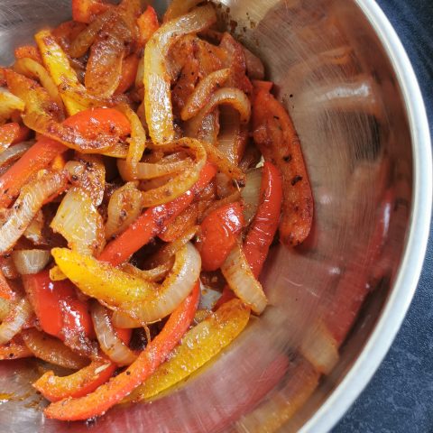 Cooked onions and peppers in a silver bowl